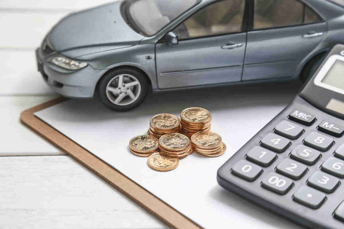 Immagine con una calcolatrice, delle monete e il modellino di un'auto
