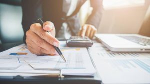 Persona che fa i conti con la calcolatrice e scrive